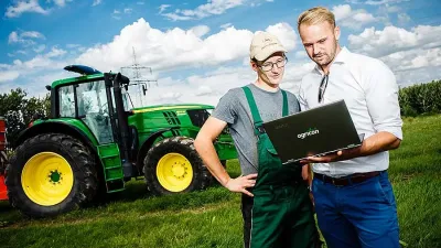 Dva muži u traktoru John Deere si prohlížejí notebook Agricon.