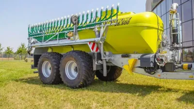 Zelenožlutá cisterna Fliegl PolyLine odstavená na trávníku.