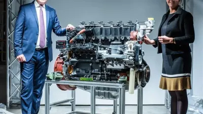 Motor Deutz vystavený na stojanu mezi dvěma lidmi.