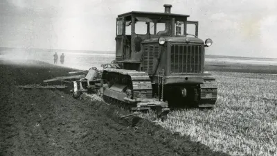 Historický sovětský pásový traktor při orbě pole.