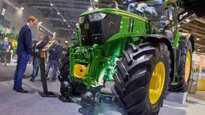 Zelený traktor John Deere vystavený v hale zemědělského veletrhu.