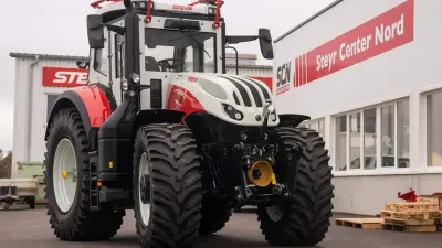 Bíločervený traktor Steyr 6300 Terrus CVT s pancéřovou kabinou před prodejnou.