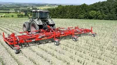 Traktor s červenými prutovými branami Einböck AEROSTAR-FUSION na poli.