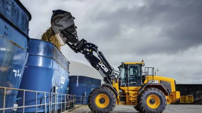 Žlutý kolový nakladač JCB 457S při nakládání siláže
