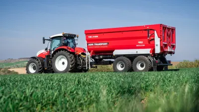 Červený traktor s návěsem Agri Transport TDK 21000 na poli