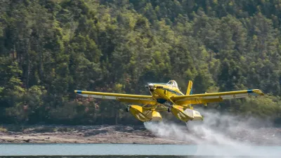 Žlutý hasicí letoun Air Tractor nabírá vodu nad hladinou přehrady.