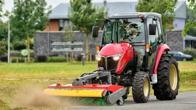 Červený malotraktor Yanmar s čelním žacím strojem při práci.