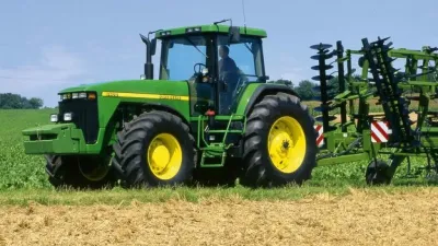 Zelený traktor John Deere 8400 na poli.