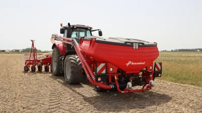 Traktor s červeným čelním zásobníkem Kverneland f-drill na poli.