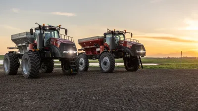 Dvě autonomní rozmetadla Case IH Trident na poli při západu slunce.