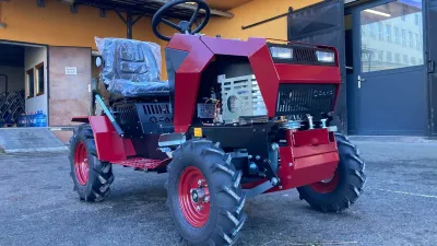 Červený stavebnicový traktor DAKR Panter FD5 před budovou.