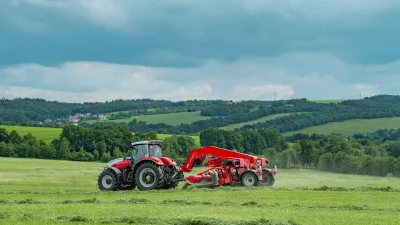 Červený traktor s pásovým shrnovačem SIP AIR 900 T při sklizni píce.