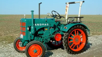Historický zelený traktor Hanomag s oranžovými koly.