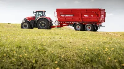 Červený dvounápravový návěs AGRI TRANSPORT za traktorem.