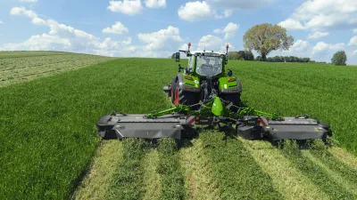 Traktor se širokým žacím strojem Fendt Slicer při sečení louky.