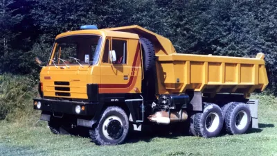 Žlutý sklápěč Tatra 815 na travnaté ploše.