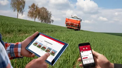 Tablet a telefon s aplikací Rauch před rozmetadlem na poli.