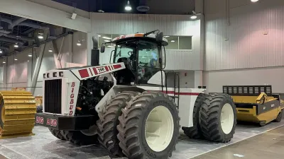 Bílý kloubový traktor Big Bud ve výstavní hale.