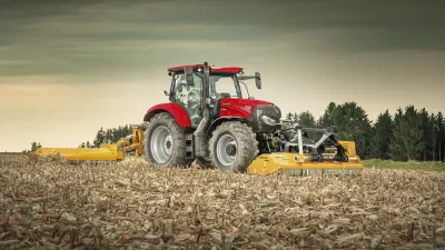 Červený traktor Case IH Maxxum s nářadím na poli.