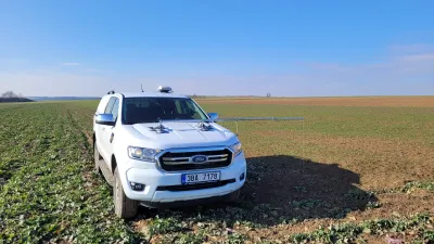 Bílý automobil Ford s anténami navigace na poli