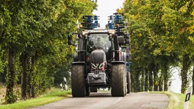 Traktor Valtra na silnici mezi stromy