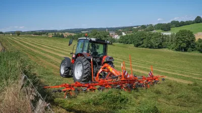 Traktor s oranžovým obracečem Kuhn na louce