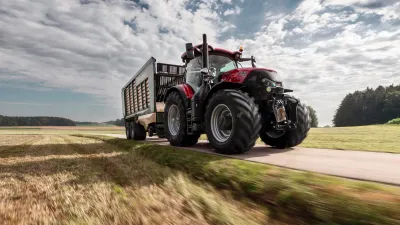 Červený traktor Case IH Optum s přívěsem na silnici