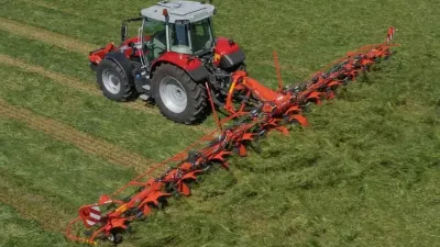 Traktor s širokým obracečem Kuhn při práci na louce