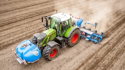Zelený traktor s čelní nádrží Lemken SprayHub při setí na poli