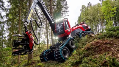 Červený lesní harvestor Komatsu ve svahu mezi stromy