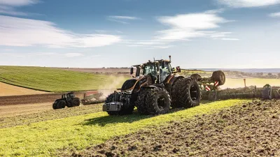 Tmavý traktor Valtra série S s nářadím při práci na poli