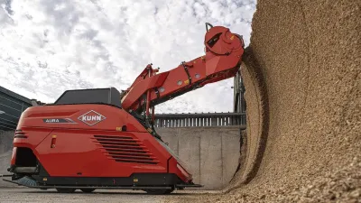 Červený autonomní krmný vůz Kuhn Aura odebírá krmivo ze siláže