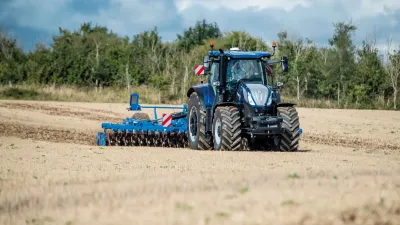 Modrý traktor New Holland T7 s diskovým nářadím na poli