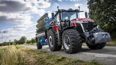 Traktor Massey Ferguson 9S s modrým nářadím na silnici