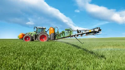 Traktor s postřikovačem Amazone stříká porost na poli