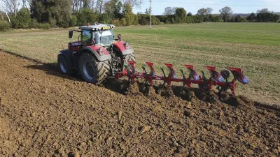 Traktor s červeným pluhem SUKOV při orbě