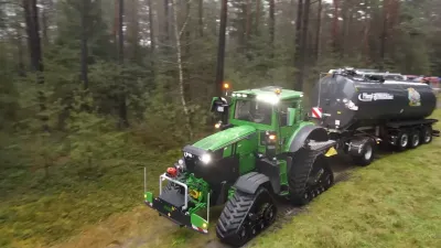 Obrněný zelený traktor John Deere s cisternou na lesní cestě
