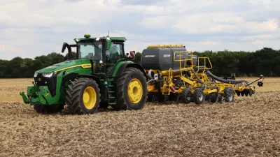 Traktor John Deere se žlutým secím strojem na poli