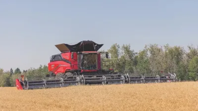 Červená sklízecí mlátička Case IH AF11 s širokým žacím adaptérem na poli