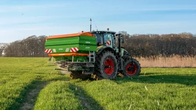Traktor s rozmetadlem Amazone aplikuje hnojivo na zeleném poli