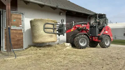 Nakladač Weidemann převáží kulatý balík sena u stáje