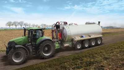 Traktor táhne stříbrný zemědělský návěs.