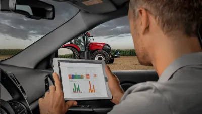 Muž v autě sleduje údaje o traktoru Case IH na tabletu.
