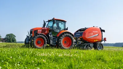Traktor Kubota s lisem na balíky na poli.
