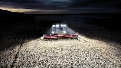 Sklízecí mlátička při noční sklizni se zapnutými světly.