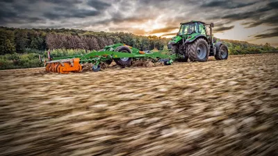 Traktor se zeleným strojem Amazone Ceus na strništi.