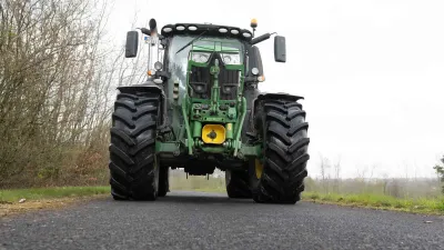 Traktor John Deere na poli s velkými zemědělskými pneumatikami.