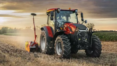 Červený traktor Case IH na poli při západu slunce