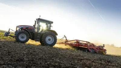 Traktor Massey Ferguson při práci na poli v protisvětle