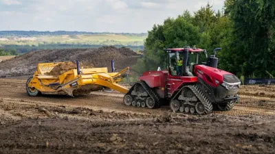 Žlutý skrejpr K-Tec naložený zeminou